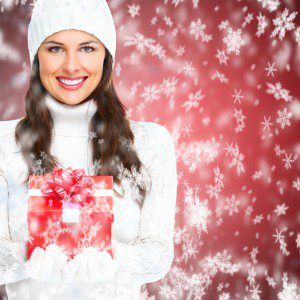 Beautiful young Christmas girl with a present over winter snow