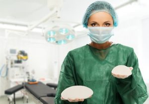 Plastic surgeon woman holding different size silicon breast implants in surgery room 